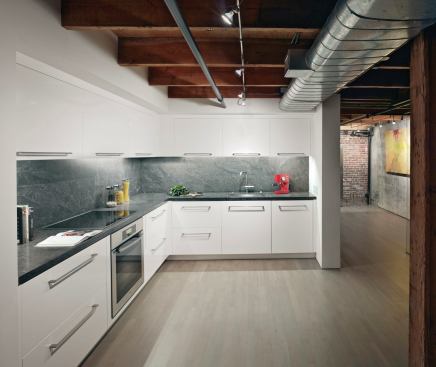 The kitchen, adjacent to the open stair, is unified with the living space. It's tucked under the heavy beams that support the mezzanine, above. 