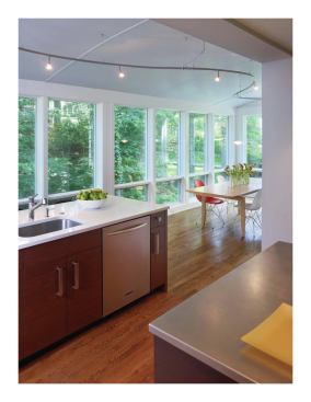 The kitchen includes two work islands, a kitchen office, and a dining area. The second island, near the window-wall, has a second sink, as well as chairs for bar-style seating. The dining area is to the right.