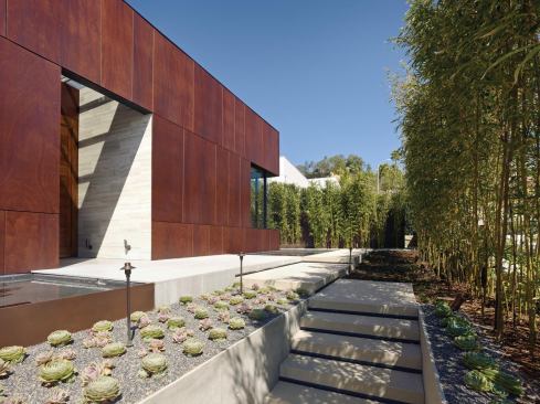 The Parlex rain screen provides a tonal counterpoint to the glass and stone. The interior’s silver travertine wall meets a mitered wood corner outside the entryway.