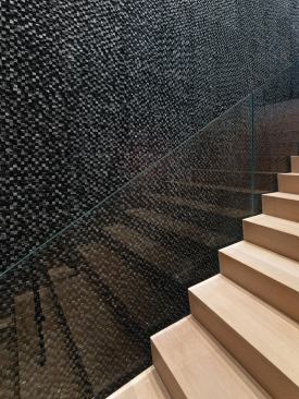Water flows over a stairwell wall covered in dark, 1-inch-by-inch irregular mosaic tiles.