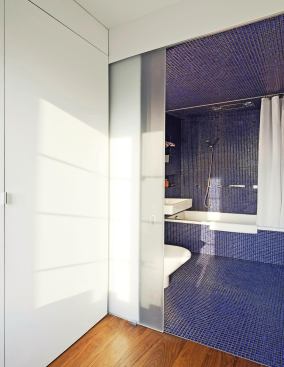 The new bathroom features blue tiles and frosted glass doors.