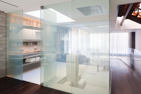 The bath separates the master bedroom from a private study, but its transparency creates the sense of a single continuous space.