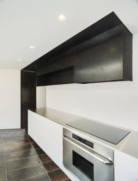 Knife-edge stainless steel counters top the gloss-white base cabinets. The uppers are acid-washed steel.