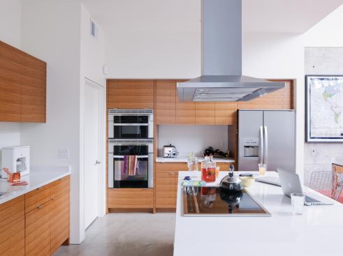 The home integrates a streamlined kitchen into adjoining living and dining spaces.