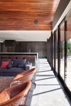 The kitchen is flush, minimal, and hidden away behind clear-coated blackened steel panels.