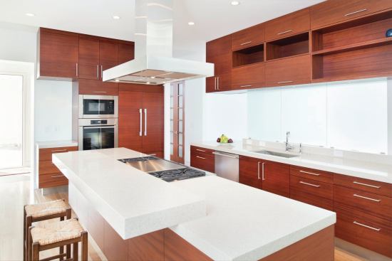 The island with the cooktop has an extra slab of quartz composite, a sculptural element that separates the seating from the prep area. 