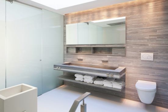 A custom vanity features a wide trough sink and shelves for towels.