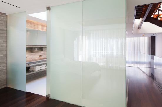 Luxury touches like a stone wall wth faucets embedded in it and a custom vanity work in concert wtih the privacy glass for a deluxe, space-age effect. 