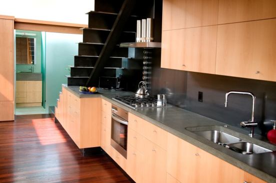 The ktichen is tucked beneath an exposed steel staircase.