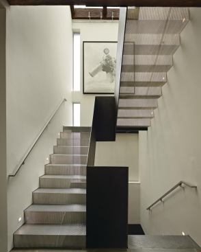 Stair runs fabricated from folded sheets of perforated steel filter light from a skylight above.