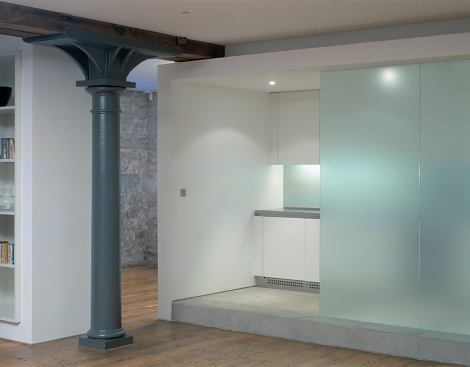 The kitchen’s minimal, hard-edged palette was a response to the robust simplicity of the old building, which features heavy timber floors and cast iron columns.