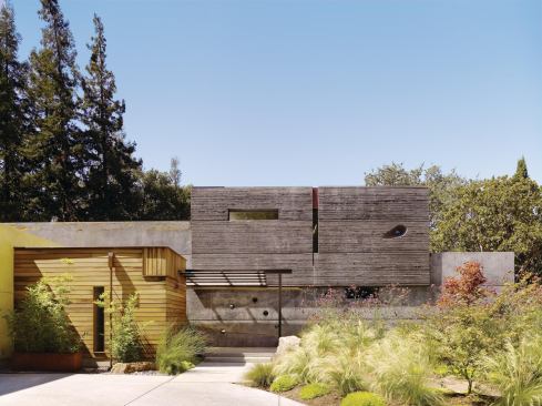 The home's refined-looking, slipcast concrete contrasts with a heavily textured, board-formed concrete element on the front elevation, as well as portions clad in reclaimed wood.