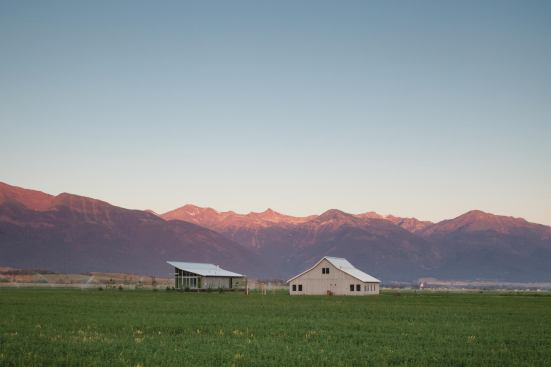 The sloped roofline of the farmhouse echoes that of the nearby barn.