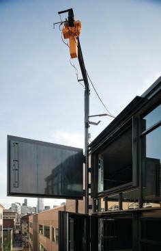 A davit crane perches atop the back of the building, connecting to a vertical, 80.5-foot-tall hinge.