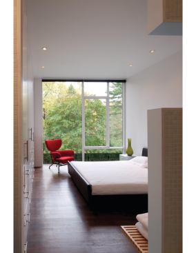 A large window in the master bedroom frames leafy views.


