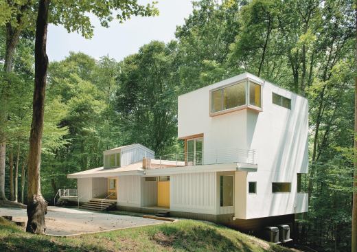 The owners of this house loved the tree-filled property, but the original cabin-like house didnt reflect their style. For the renovation, they turned to KUBE architecture, a Washington, D.C., firm known for its modern aesthetic. The homeowners original plan was for a small master bedroom addition. However, the project evolved to a larger tower addition with a master suite and a library/living area. A deck off the tower connects the addition to the original house.