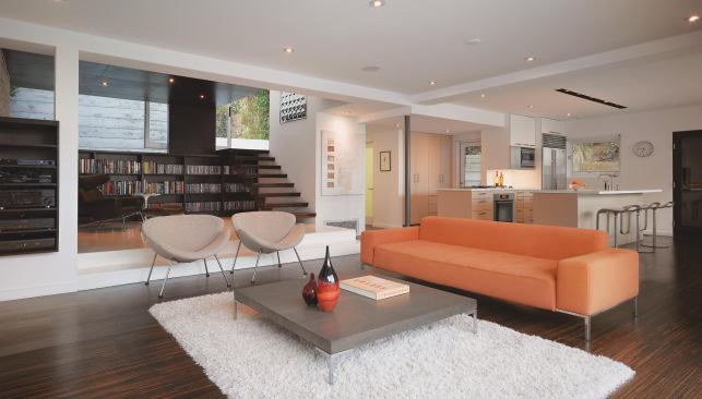 The open library is part of a small addition that includes an upstairs guest room. A 12-inch step and a contrasting color palette (light floor and dark ceiling) help separate it from the living room.