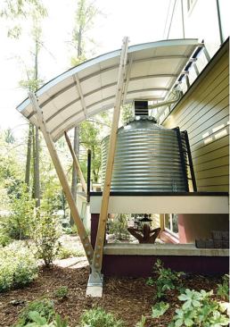The 1,000-gallon CorGal steel tank collects and stores rainwater. Below it is an outdoor shower. The home uses a geothermal system for heating and cooling and for hot water.  