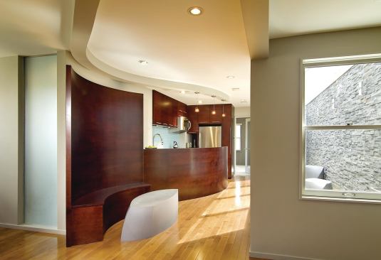 This 1,000 square-foot apartment lacked flow and had little natural light. KUBE Architecture, of Washington, D.C., stepped in to maximize the small space. The designers created an open living area with a sweeping wood wall that is both sculptural and functional.
