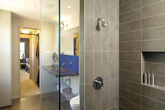 The bathroom has two entries. A frosted glass door leads to the living area on one side and the dressing room/bedroom on the other side.