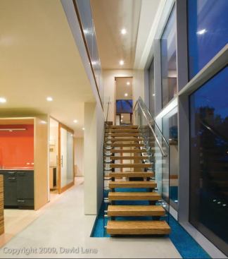 Recycled blue glass creates the illusion of a pool under the glass staircase. Large expanses of glass and sliding interior doors bring natural light to all areas of the house.