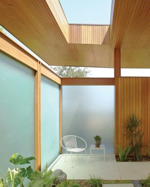 Frosted glass panels enclose a private outdoor space lit from above by large roof opening.
