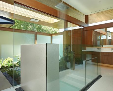 A wall of frameless glass joins this remodeled master bath with a private courtyard. The terrazzo floor folds down into a sunken tub shower.

