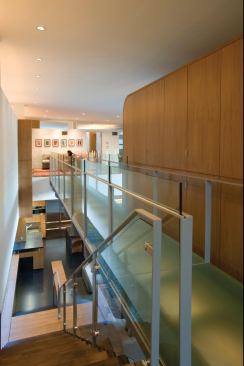 A glass bridge connects the slatted volume to a playroom on the house's opposite side.