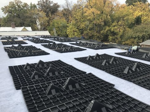 The plastic bases for the PV arrays lie on the roof ready to receive racking elements.