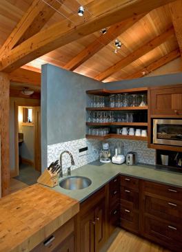 The kitchen, separated from the rest of the room by a breakfast bar, features cabinets and shelving crafted from reclaimed walnut.