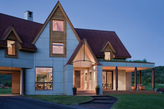 Modest additions of a porch and breakfast bay wear a roof planted with meadow grasses.