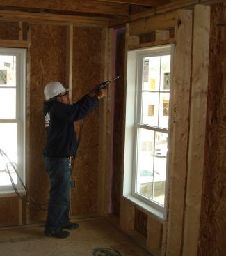 A contractor performs air sealing with Owens Corning's EnergyComplete system.