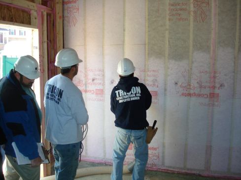 A contractor blows in fiberglass insulation, which provides better coverage than batts.