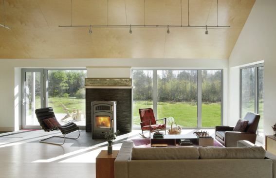 A stone hearth and finish-grade plywood add visual warmth to the Vermont residence’s minimalist interior. Triple-glazed windows contribute to the building’s ultra-efficient shell.